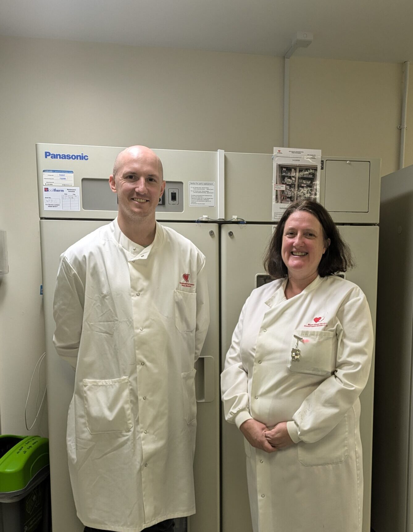Dewi Reed and Ann Jones in lab coats standing in front of cabinets